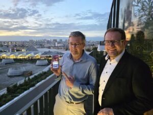 Jerome presents a mobile phone receiving 5G Broadcast on a rooftop terrace in Paris togehter with Johann
